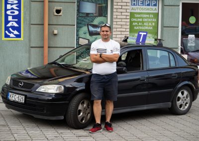 Oktató az iskola autójával az iroda előtt