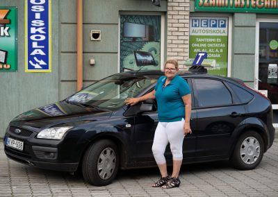 Oktató az iskola autójával az iroda előtt